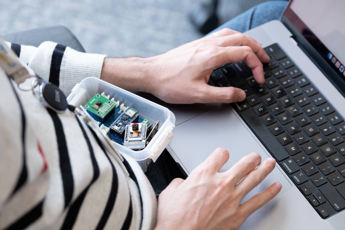 Close-up of hands working with Arduino hardware kit and laptop at workshop